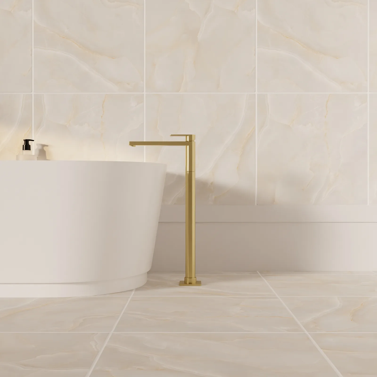 A brushed brass floor-standing tap beside the curved edge of a white bath